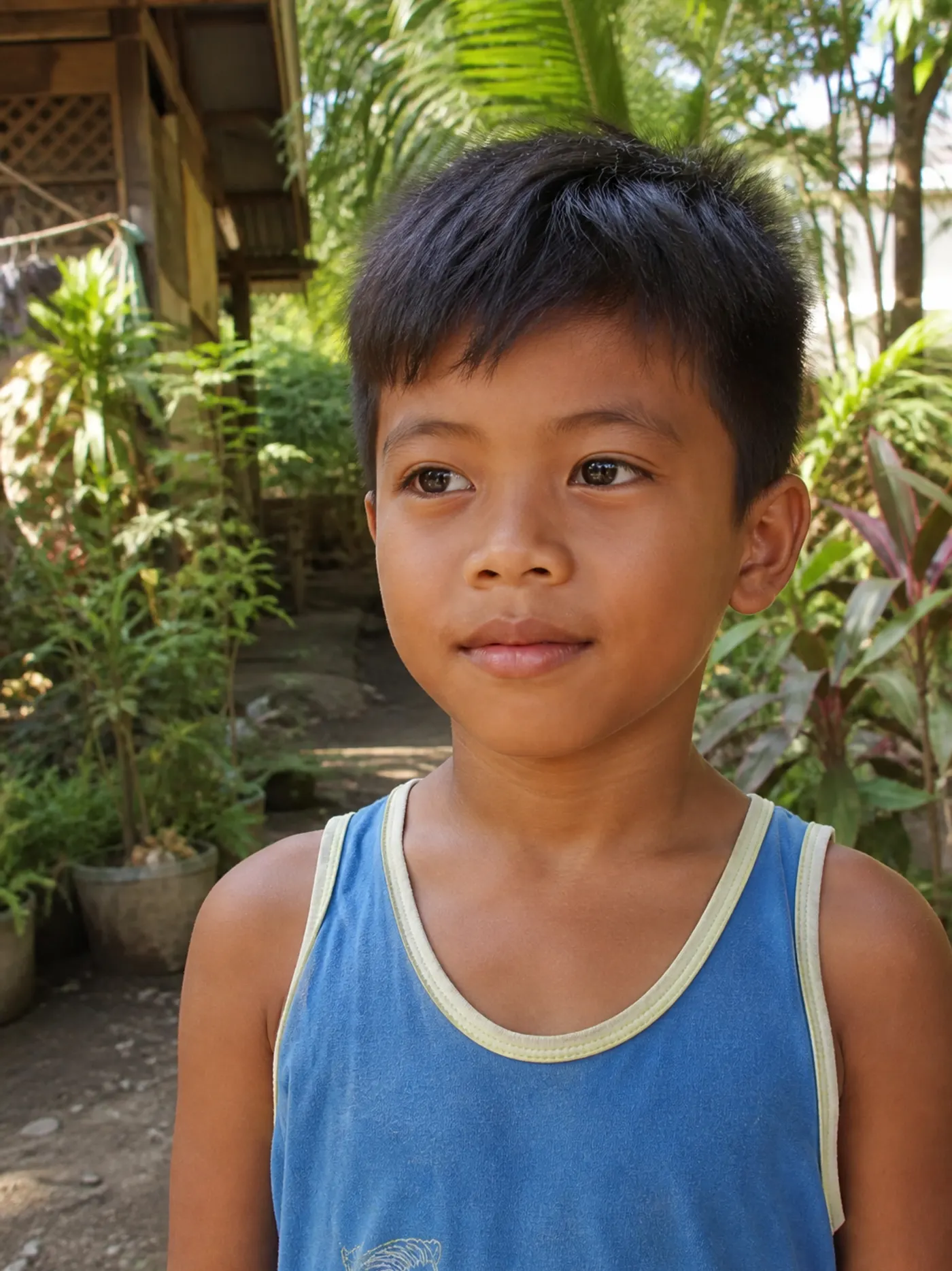 Filipino child standing outdoors in a tropical neighbourhood